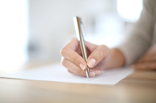 Closeup of woman's hand writing on paper